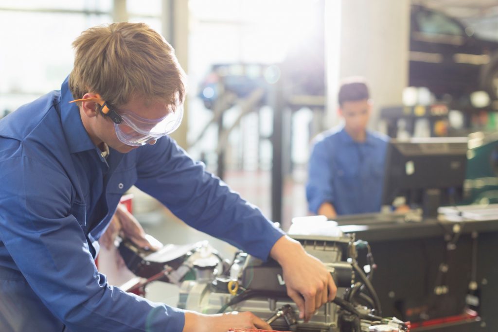 Mechanic working on engine in auto repair shop Mechanic working on engine